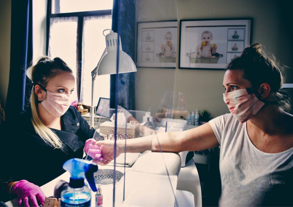 Nail technician applying gel tips to a client's nails.