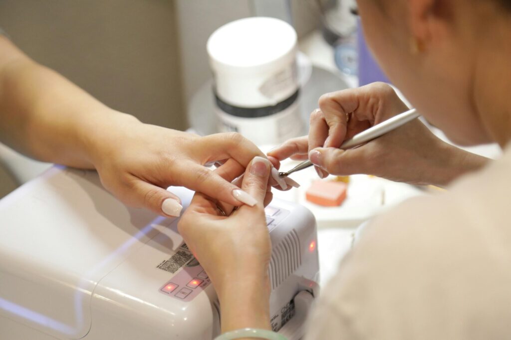 Manicurist shaping a client's nails with a nail file.