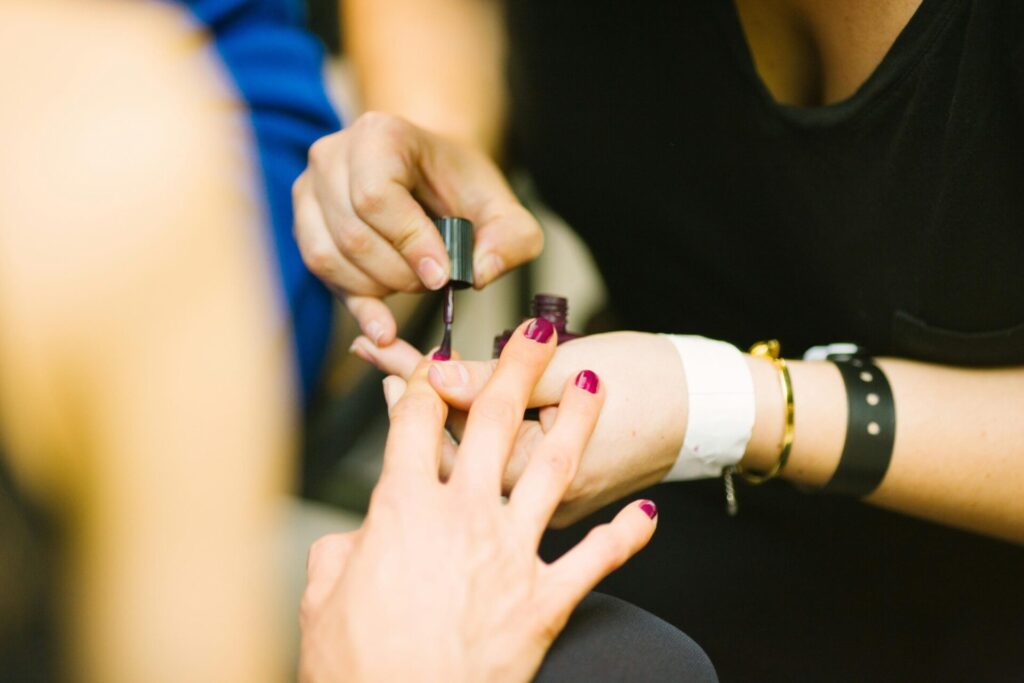 Close-up of hands as a woman applies a glossy top coat to her nails.