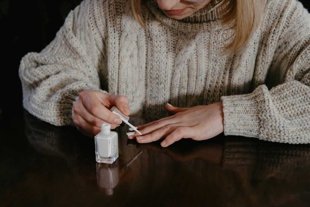 Woman using a brush to apply builder gel on her nail tips.