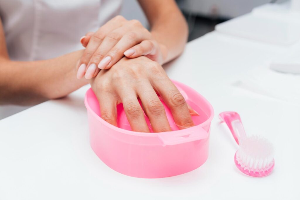 a girl soaking off her acrylic nails  , one of the maim techniques on how to get acrylic nails off